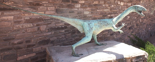 dinosaur statue on stone pedestal