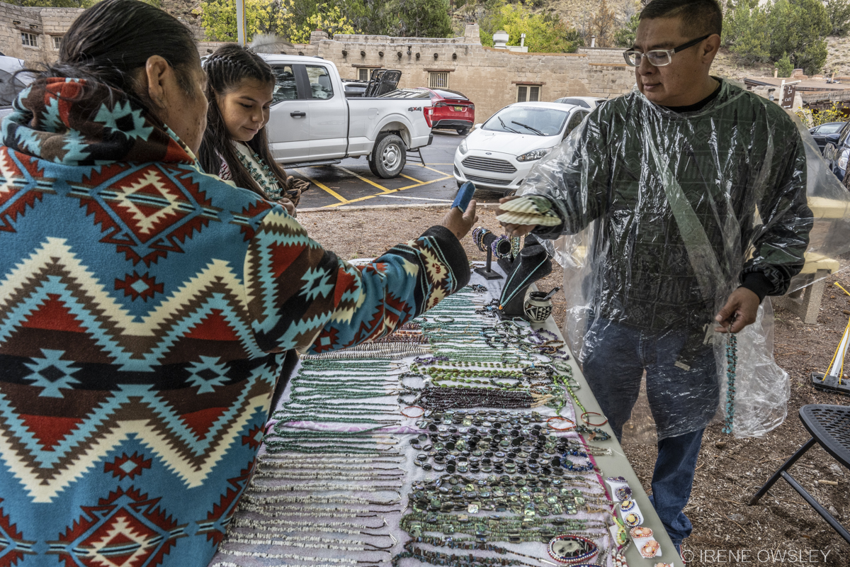 3 people stand over a table filled with local Pueblo Jewelry