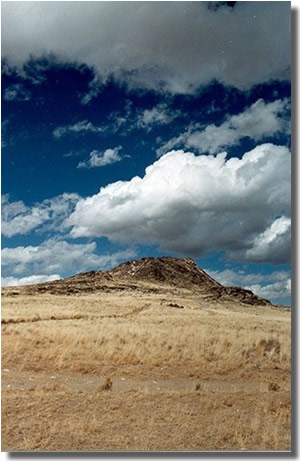 Photograph of Vulcan volcano under a dark blue sky with big white puffy clouds.