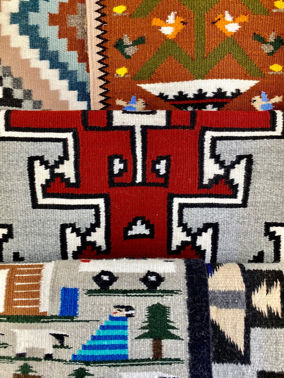 Brightly colored and patterned Navajo Rugs overlapping each other.