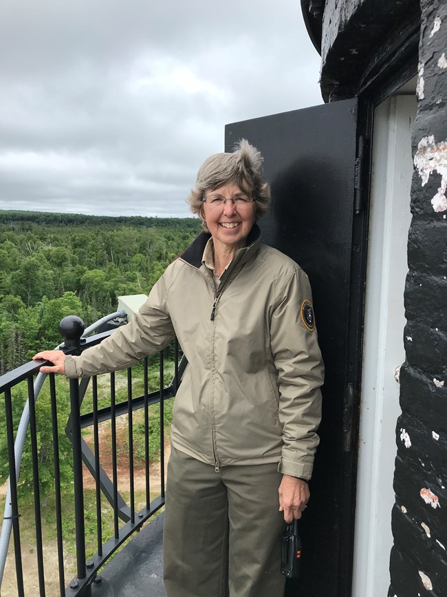 Volunteer standing on the outside walkway at the top of the lighthouse.