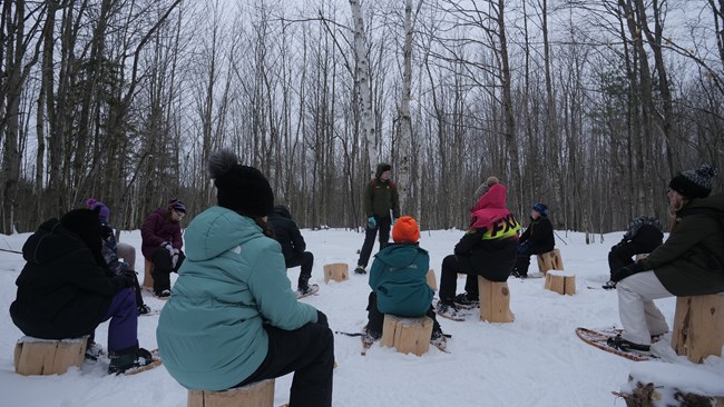 a ranger talks to a group of students sitting on logs