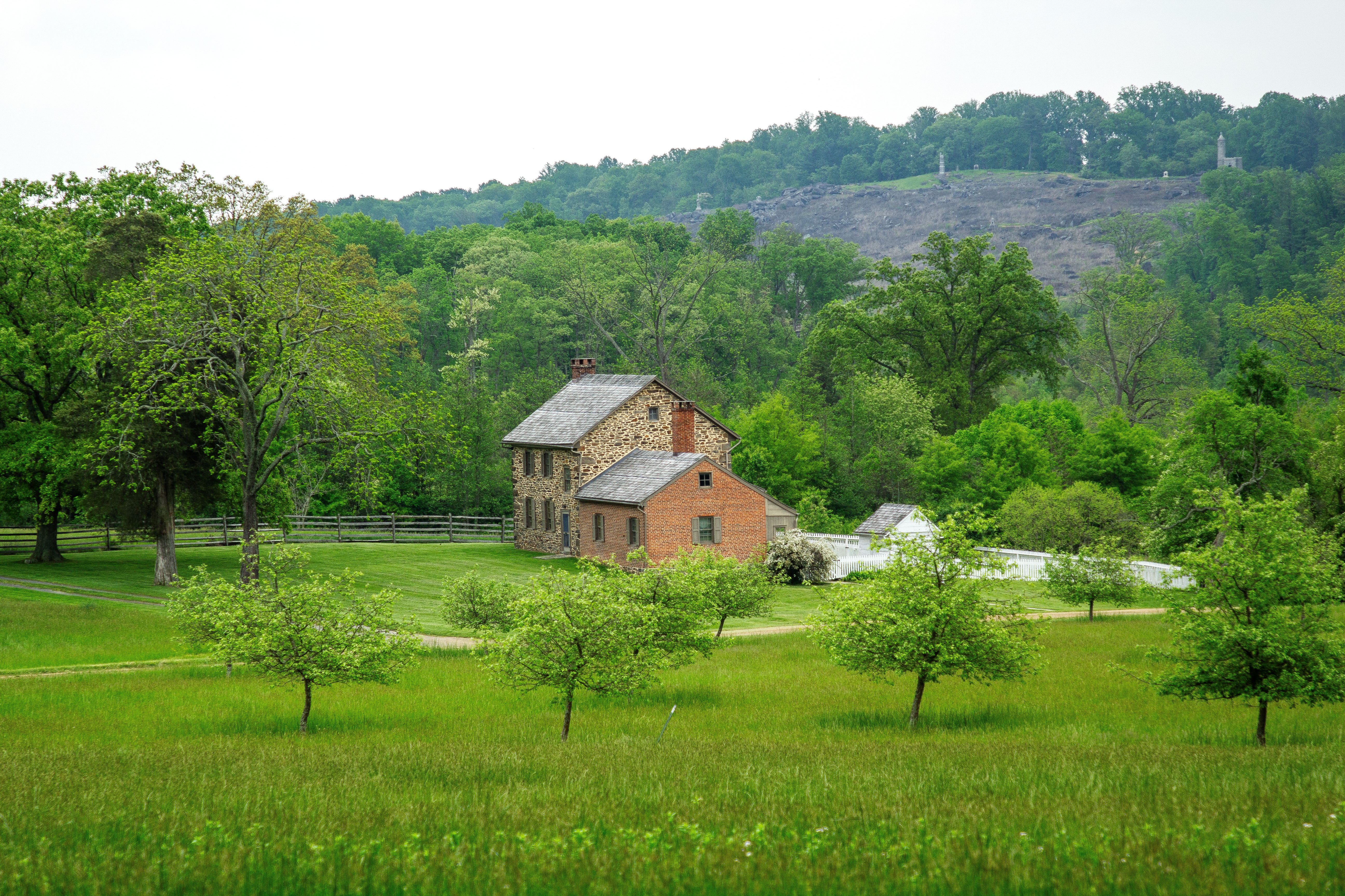 Stone house with monuments on a hill in the distance.