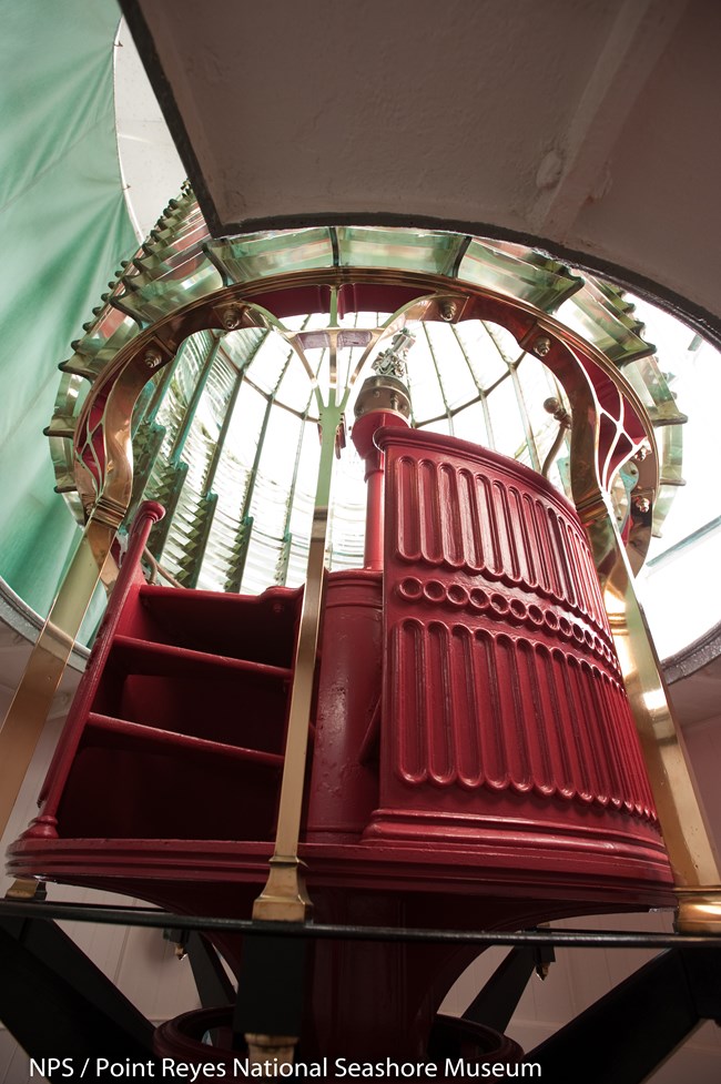 Red stairs leading up into area to change bulb in Fresnel lens at Point Reyes Lighthouse.