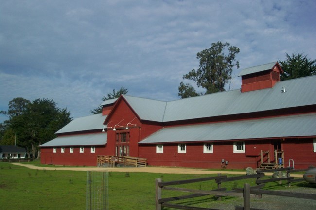A large, red, barn with a galvanized roof and windows with white trim.