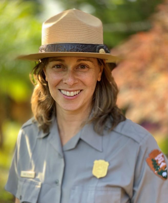 A headshot of a woman in a National Park Service uniform and flat hat.