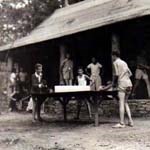 Ping pong game in front of a cabin at camp one, 1936