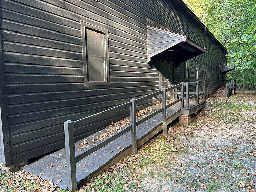 Large wooden building with ramps leading up to 2 doorways on the side in a forest