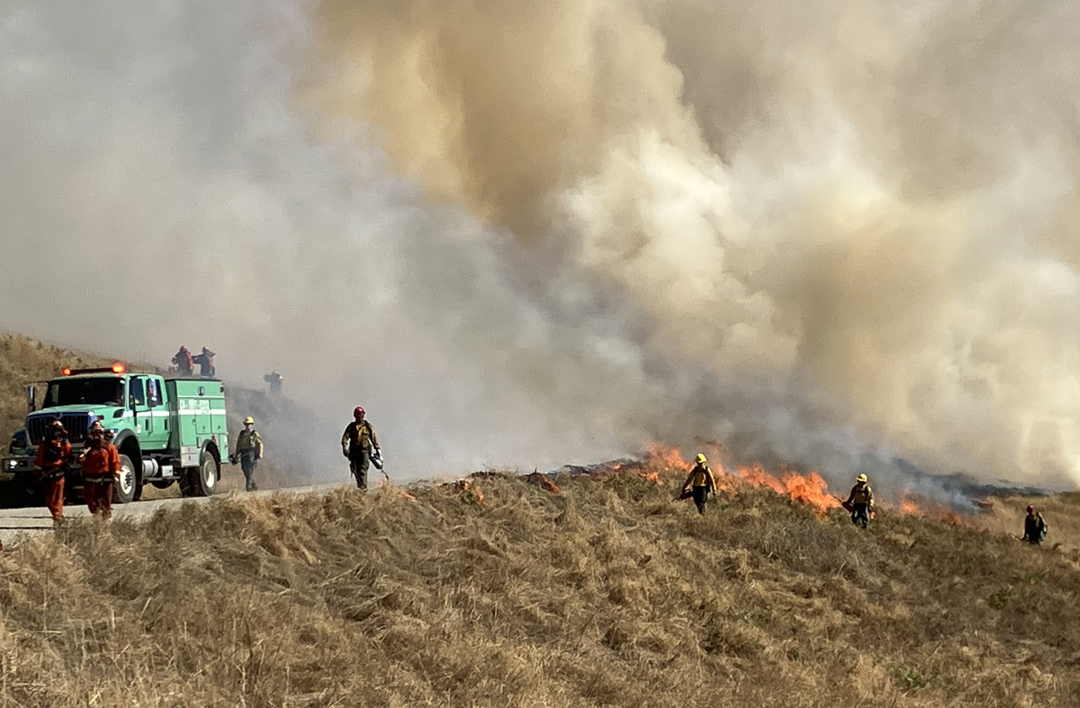 Prescribed Burn on Bald Hills in Redwood National Park. The sky is filled with smoke and there is a fire truck and crew conducting the burns.