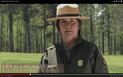 ranger in an open green field with a treeline in the background