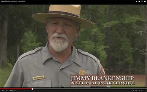 ranger in a small grassy field with trees in the background