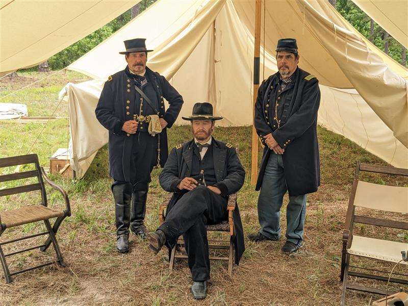 Reenactors dressed as General Ulysses Grant and his staff in front of a canvas tent.