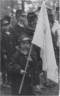 Little girl dressed in Civil War uniform jacket carries a white flag.
