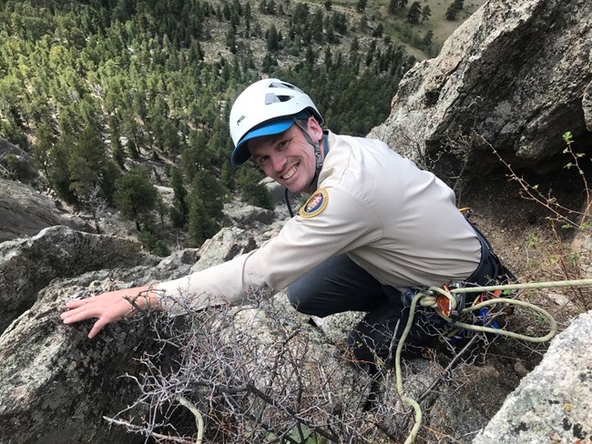 Raptor Monitoring Program Volunteer A climber looking up at the camera. He is wearing a long sleeve VIP shirt and white helmet.