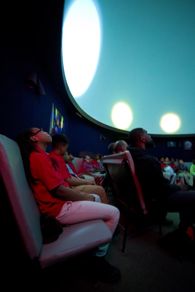 Students looking up at the dome ceiling of the planetarium during a program