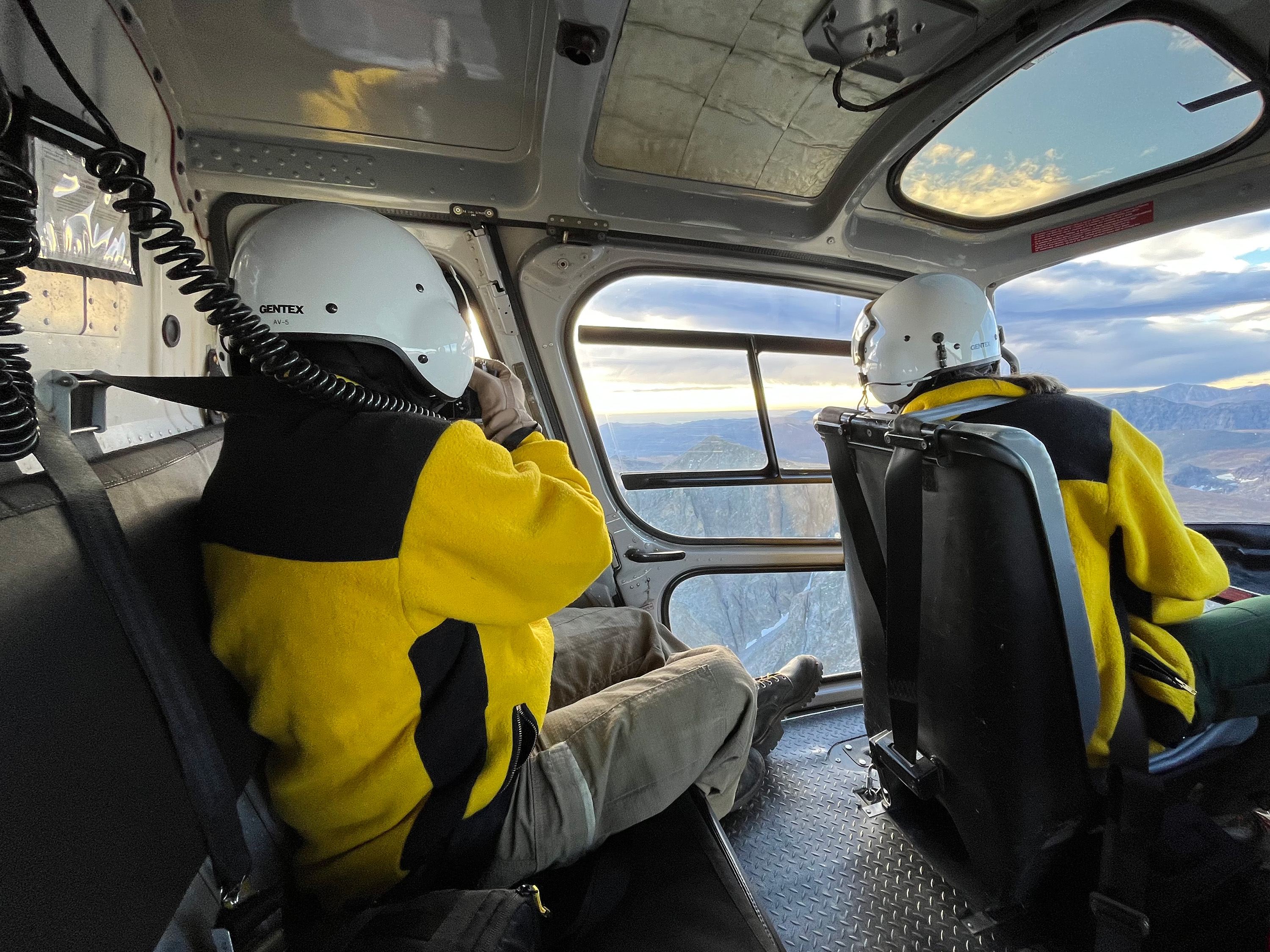 NPS Search and Rescue Team Members are in a helicopter, looking out at ridgelines for a missing man