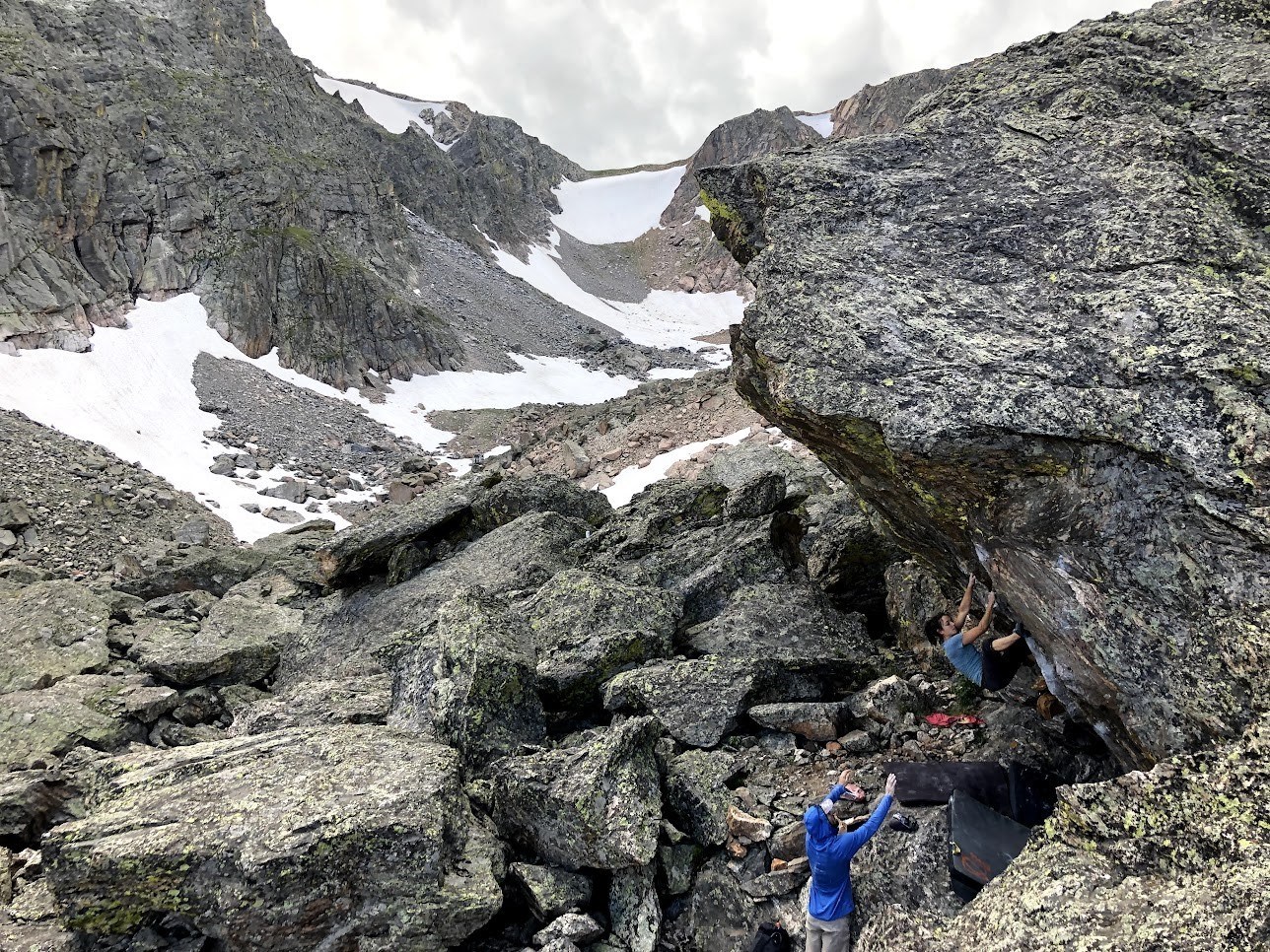 One person is spotting another climber while bouldering in RMNP.