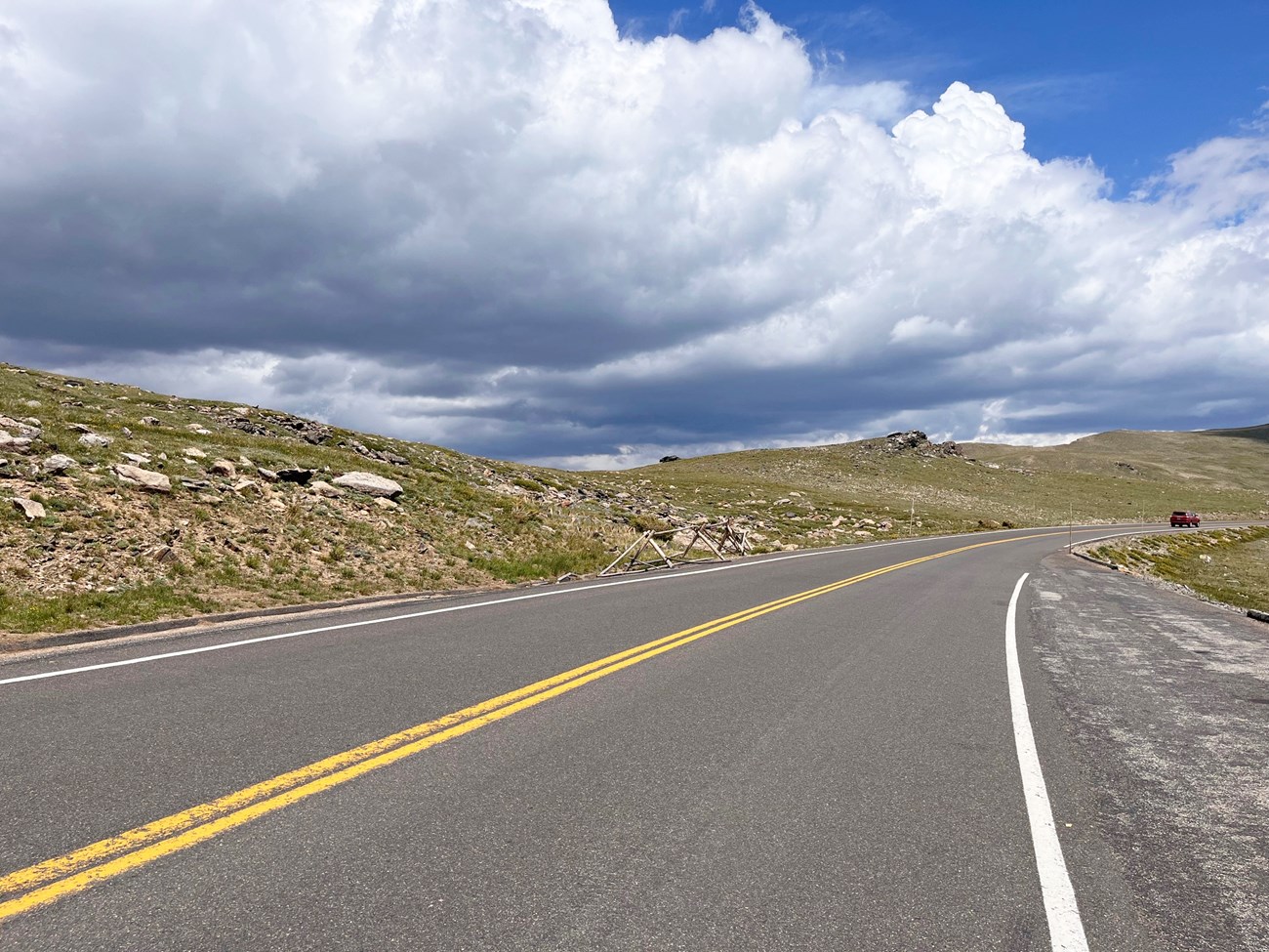 A section of Trail Ridge Road. The road surface is dry, clouds are in the sky overhead.