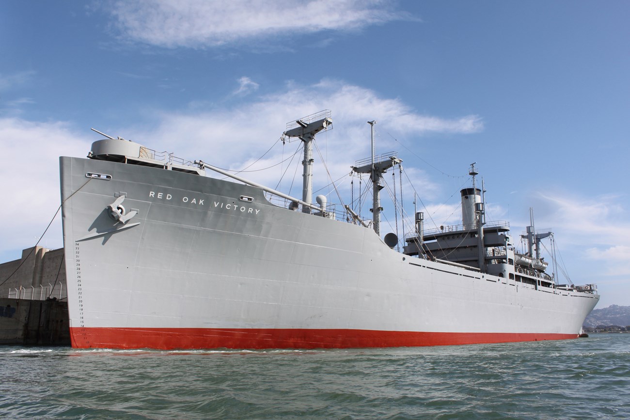 A large ship is anchored next to a concrete dock.