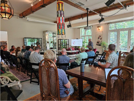 A group of people sit in attendance to a public meeting presentation