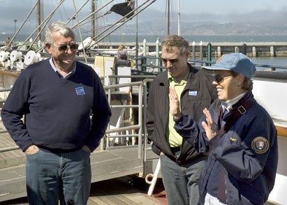 Docent Robin Mitchell speaking with two visitors aboard BALCLUTHA.