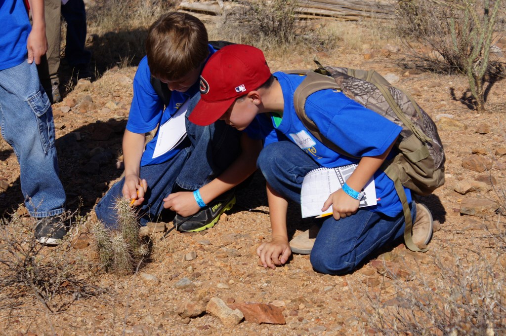 two students pointing at small cactus
