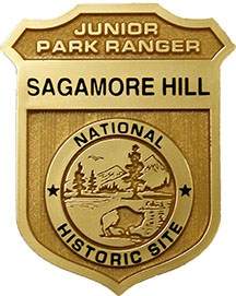 A gold shield reading, "Junior Park Ranger, Sagamore Hill National Historic Site."