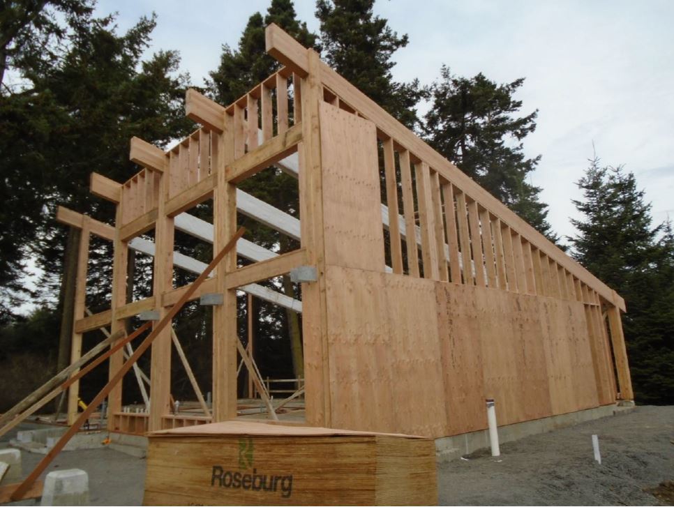 Plywood boards are placed to cover the framing on the side of building