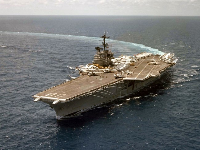 Planes are lined up on an aircraft carrier deck of a ship in the open ocean.