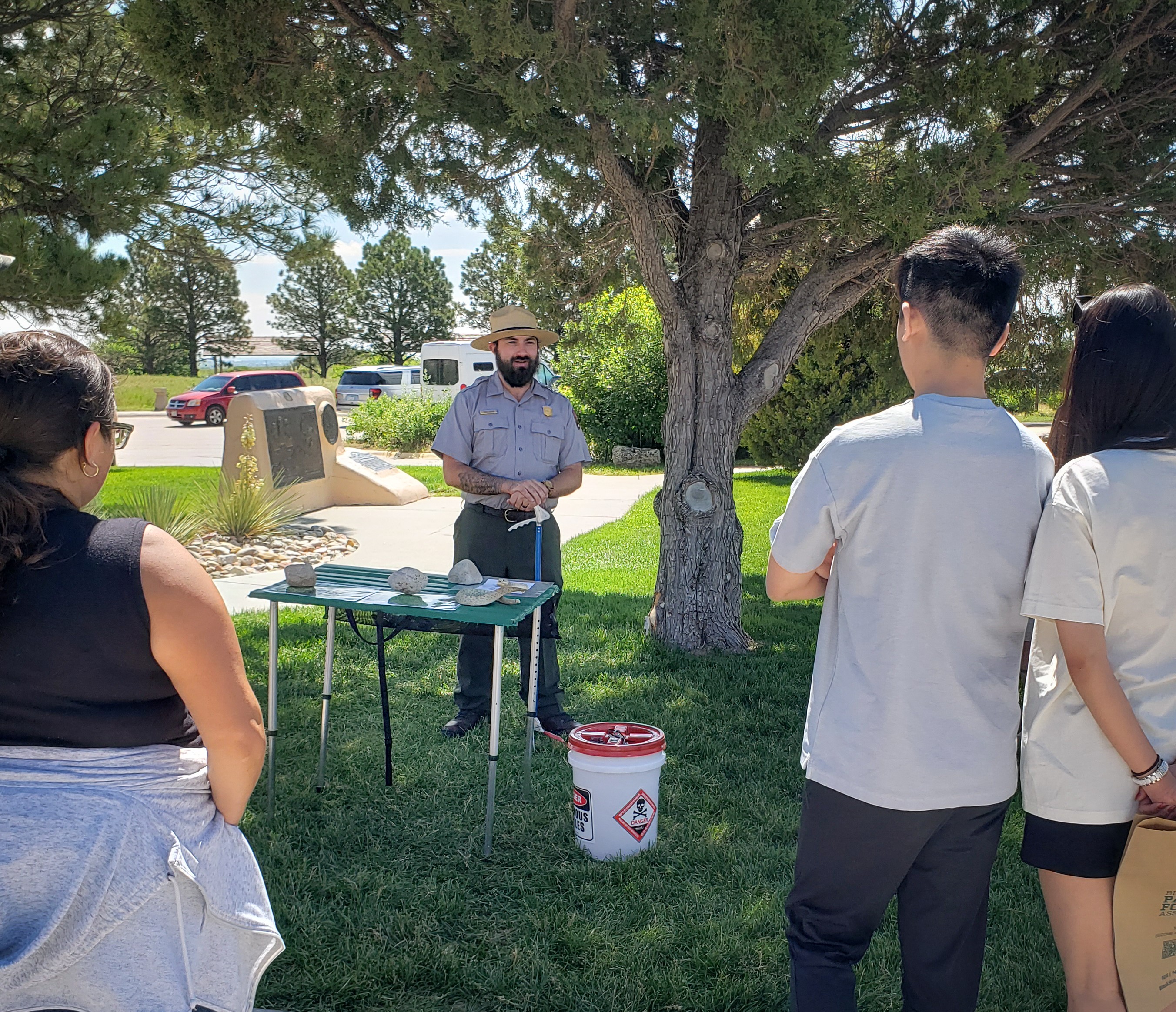 A park ranger talks to a family of three that is gathered around him.