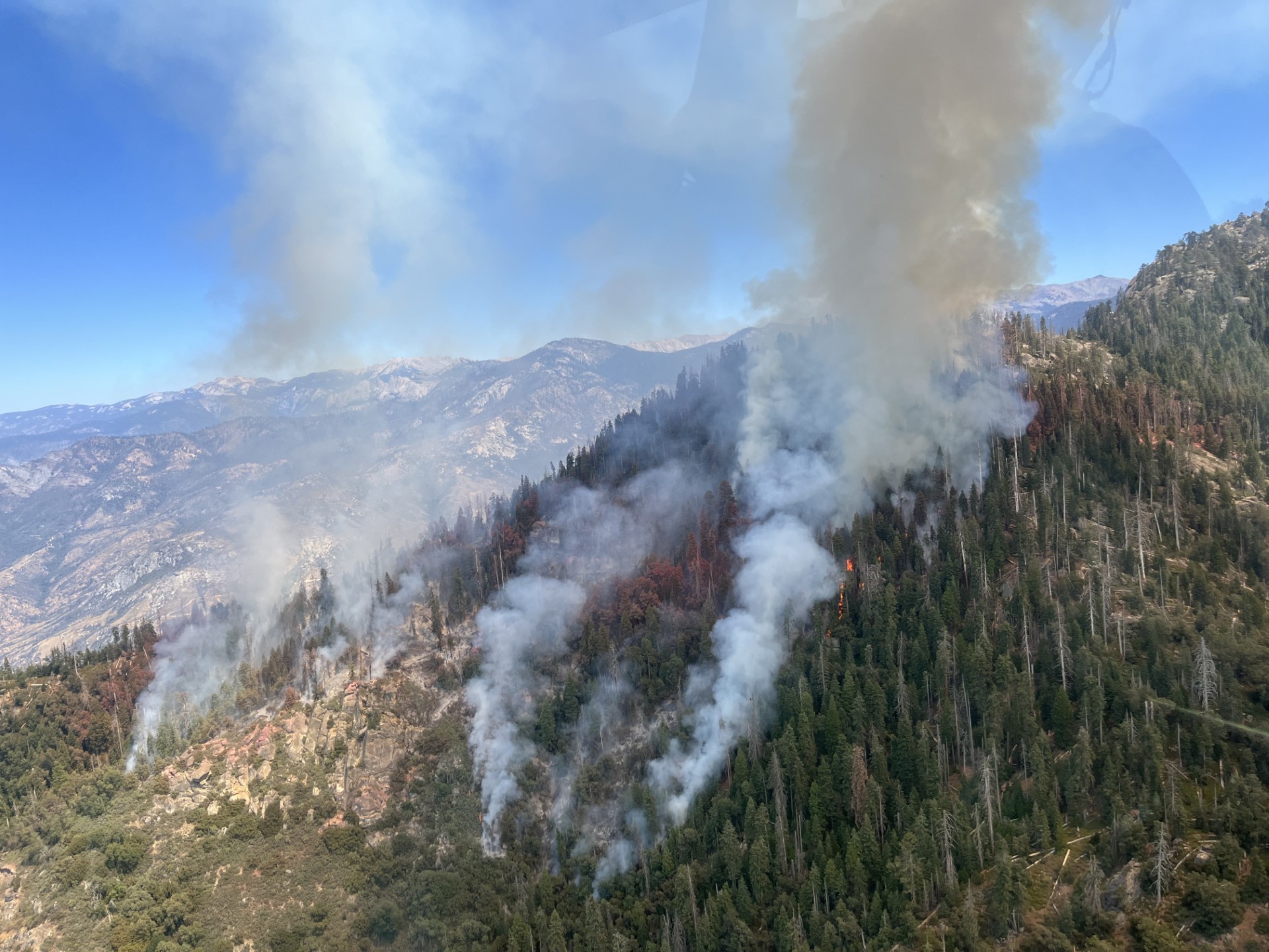 A tall mountain ridge with various patches of fire and smoke plumes.