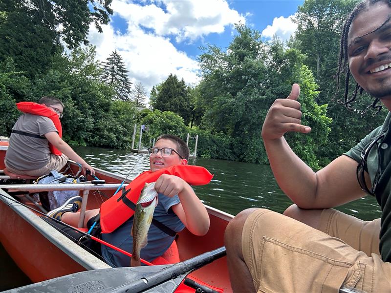 Three folks sitting in a canoe fishing