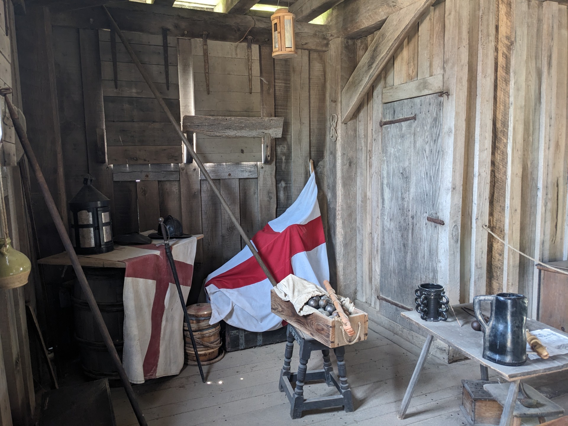 Flags, mugs, lanterns, cannon balls sit in a shed