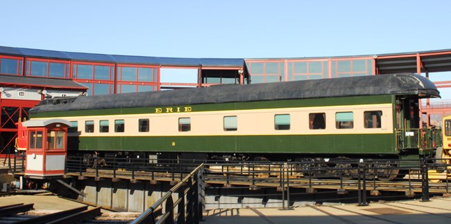 Erie Railroad Business Car #3, in green paint with yellow band surrounding car windows, displayed on Steamtown NHS turntable