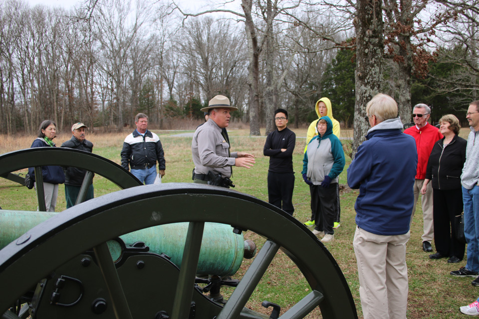 A park ranger talks to a group visitors near cannons.