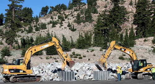 Two large yellow machines on the side of a large rock pile
