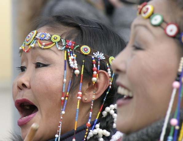 Two women in traditional dress singing.