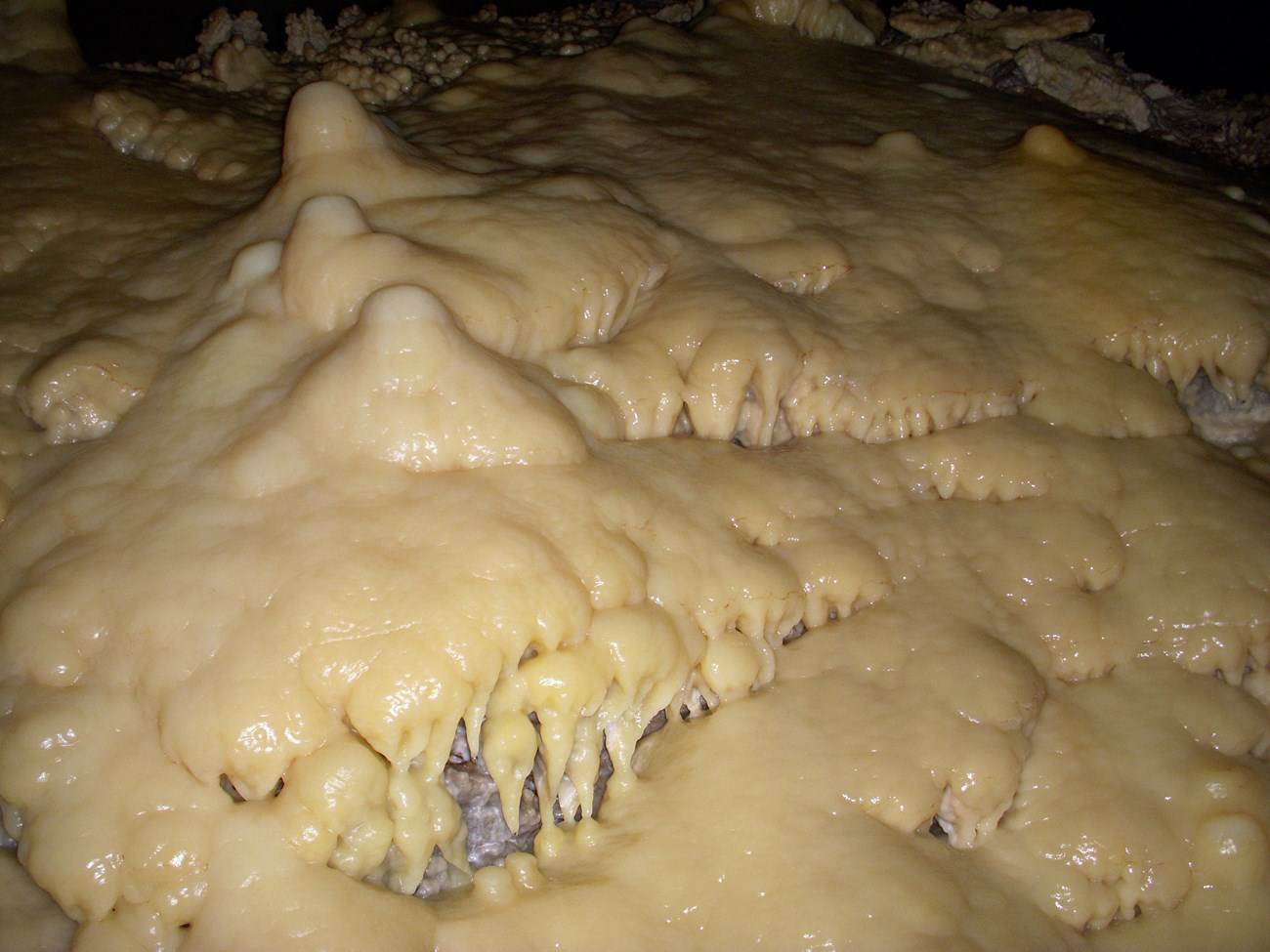 CAVE flowstone In Lechuguilla Cave NPS dale pate A light colored mineral coats the cave rocks forming "drips" and "mounds
