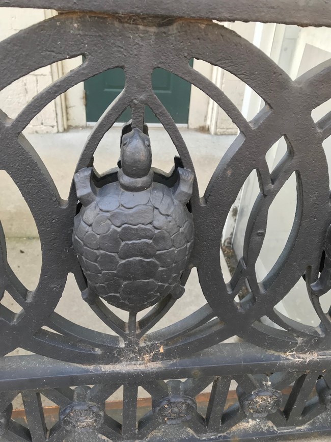 Wrought iron turtle detail within circular elements of a fence