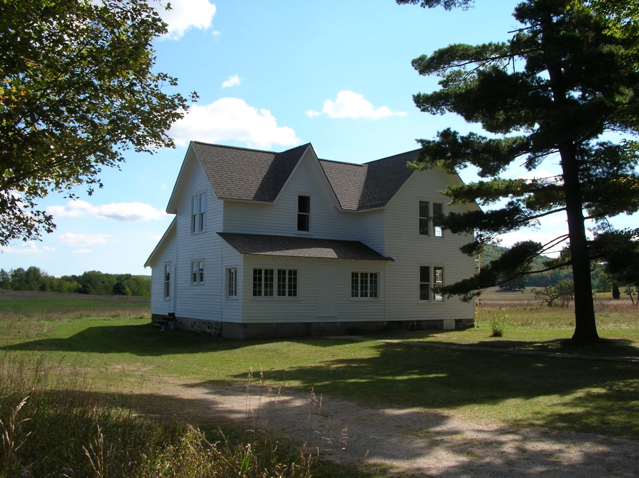 Two story farmhouse in fall in an open rural landscape at Port Oneida