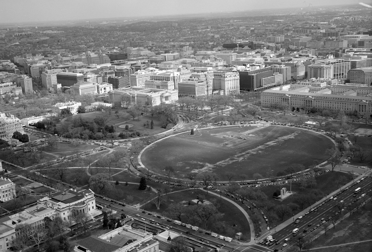 Aerial view of ellipse, a circular path around turf surrounded by park area and city streets.