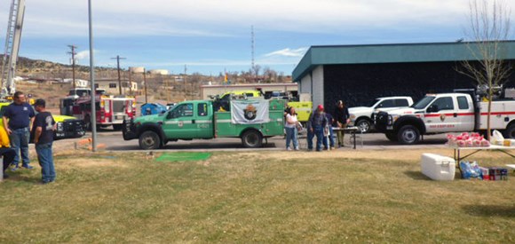 Wildland fire engines near engine bay; one with Smokey Bear flag.