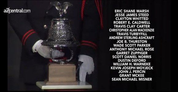 A silver bell with a member of the military honor guard standing behind.