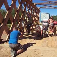 Click to see the full photo of people constructing a floor system for a covered bridge Color photo of people constructing a floor system for a covered bridge