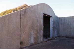 Sloped cement wall with an empty door frame.