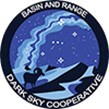 Basin and Range Dark Sky Cooperative logo. Blue hue of entire logo, huge milky way crossing over mountains