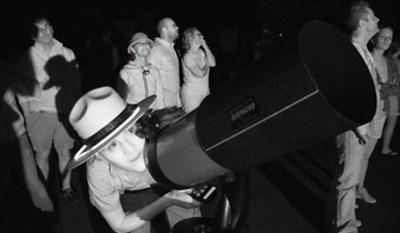 lt= A ranger with Dead Horse State Park looks through a telescope for a view to the night sky.