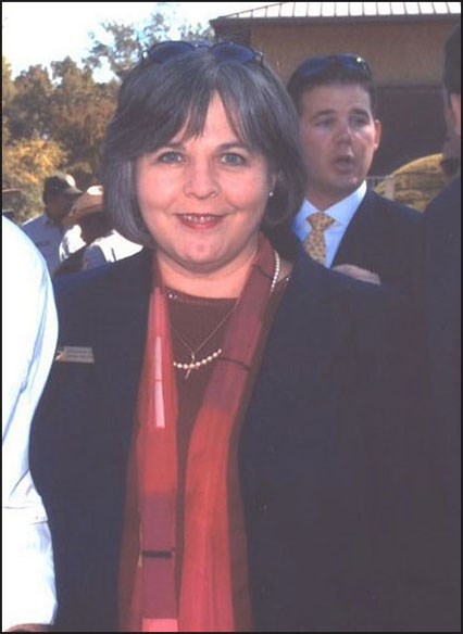 Kathleen Bond smiles for a photo, standing in a crowd outdoors
