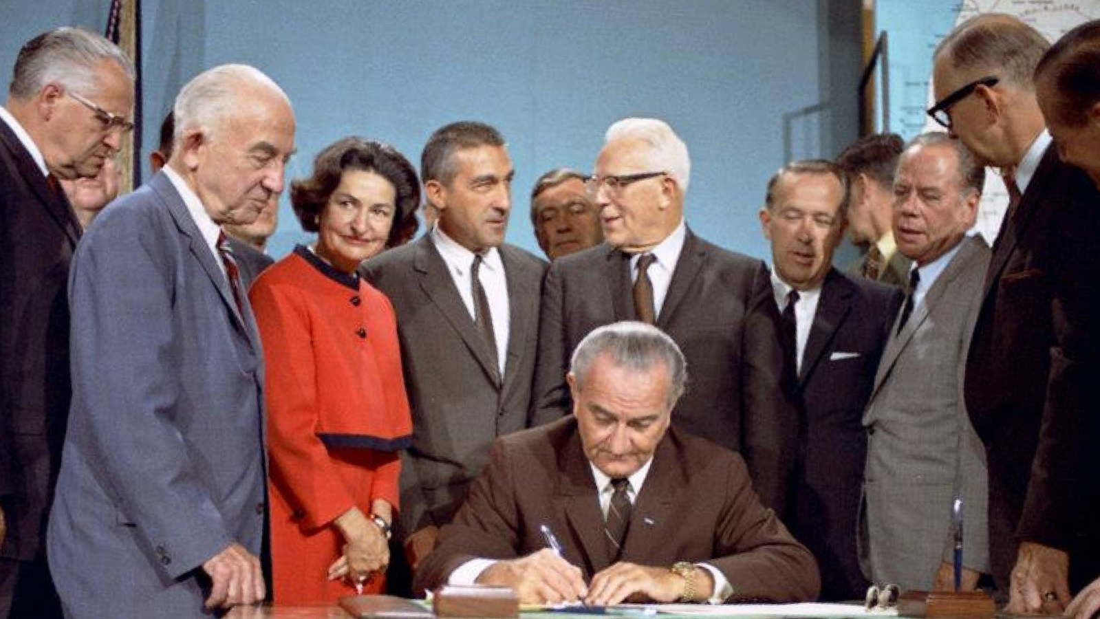 Lyndon B. Johnson signing WSRA in 1968 Lyndon B. Johnson sitting at a desk signing the Wild and Scenic Rivers Act surrounded by others standing around him