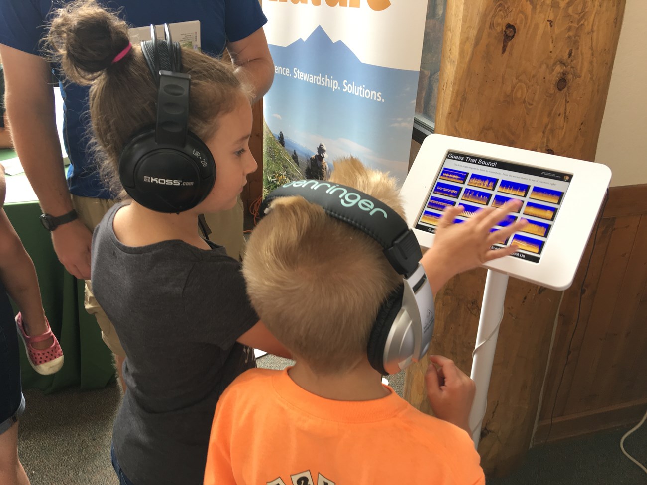 Children learning about soundscapes: Guess That Sound Rear view of two children interacting with a touch screen displaying spectrograms.